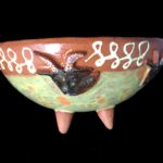 Earthenware bowl with painted goats and slip detail.